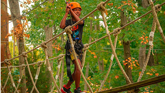 A boy going over the Family Adventure Park Course in the fall over a bridge
